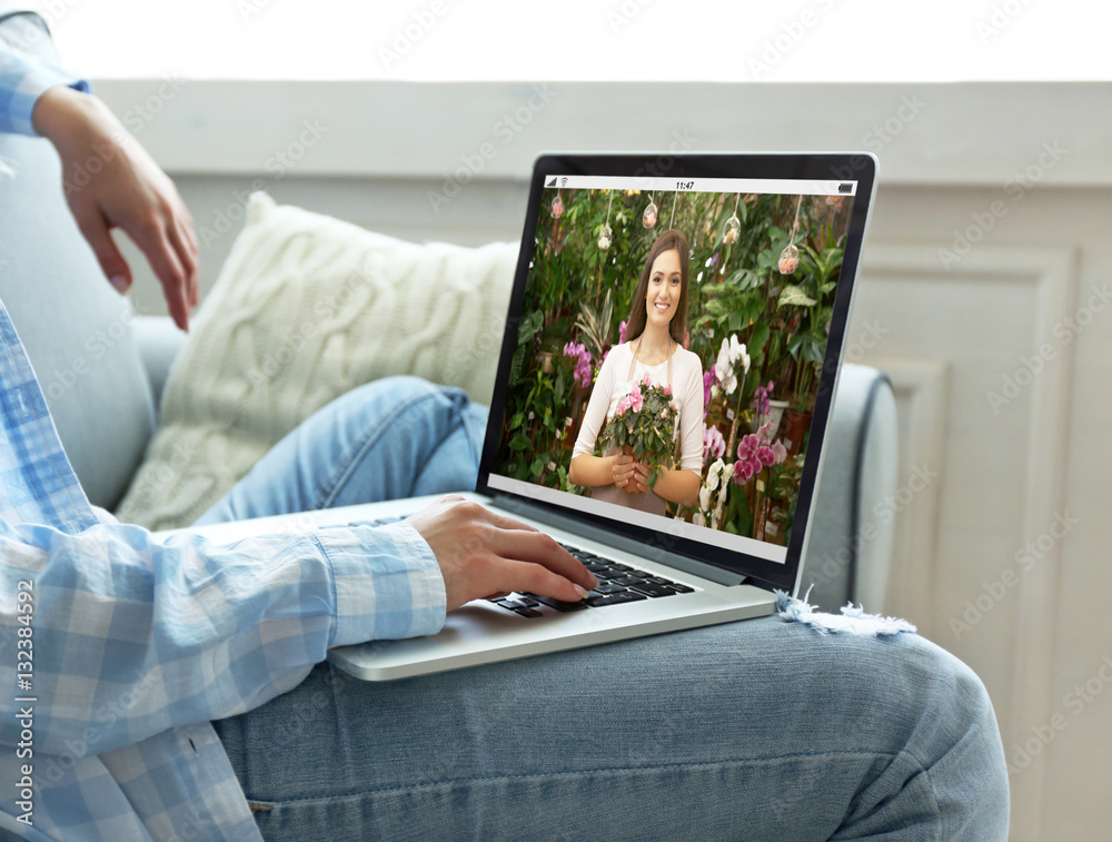 Fototapeta premium Video call and chat concept. Modern communication technology. Woman ordering flowers delivery online via laptop.