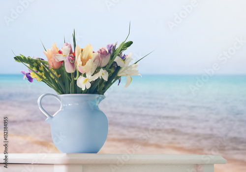 Fototapeta Naklejka Na Ścianę i Meble -  Beautiful bouquet in jug on table against seascape background