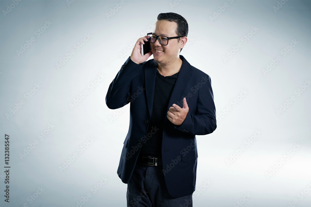 Happy smiling businessman wearing black suit and using modern smartphone with points a finger pose. Happy smiling businessman wearing black suit and using modern smartphone with points a finger pose.