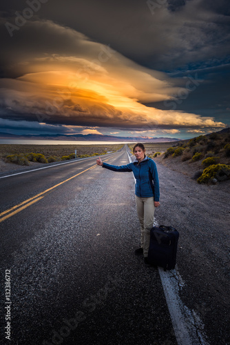 Hitchhiking on a desert road at sunset