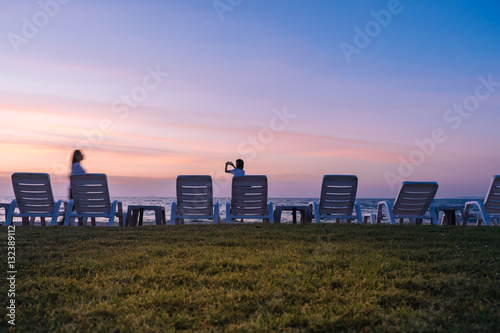 Woman takes pictures on the phone at sunset near the sea.