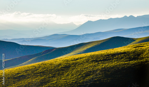 The sunset layers of mountains, vast background material. © liuzishan