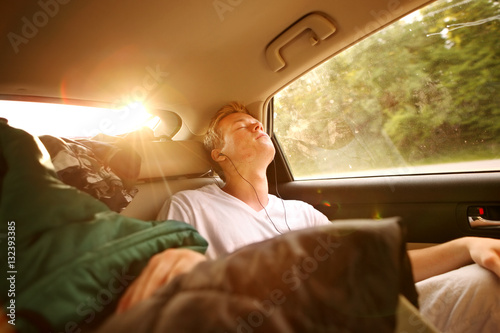 Obraz na plátně Teenager sleeping in the backseat of a car on a trip