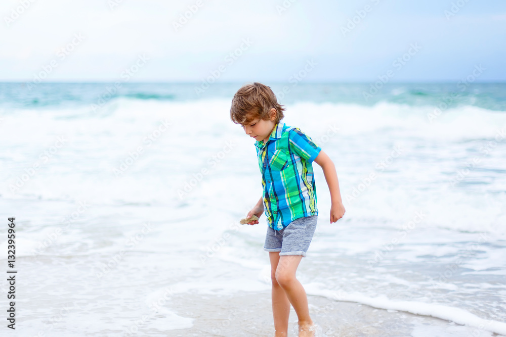 little kid boy running on the beach of ocean