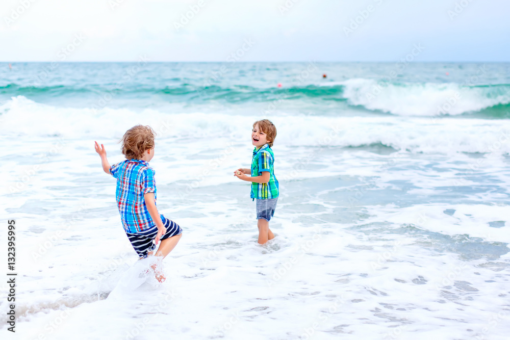 Two little kids boys running on the beach of ocean Two little kids boys running on the beach of ocean