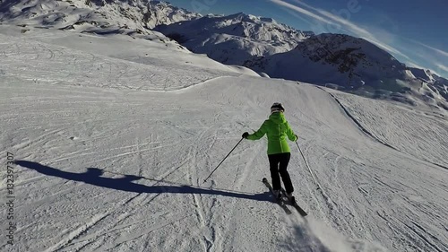 Slow motion: Young woman is skiing down on slope on sunny day, Tignes, France