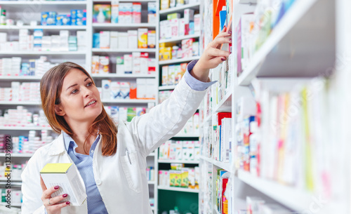 Photo of a professional pharmacist checking stock in an aisle of a local drugstore. photo
