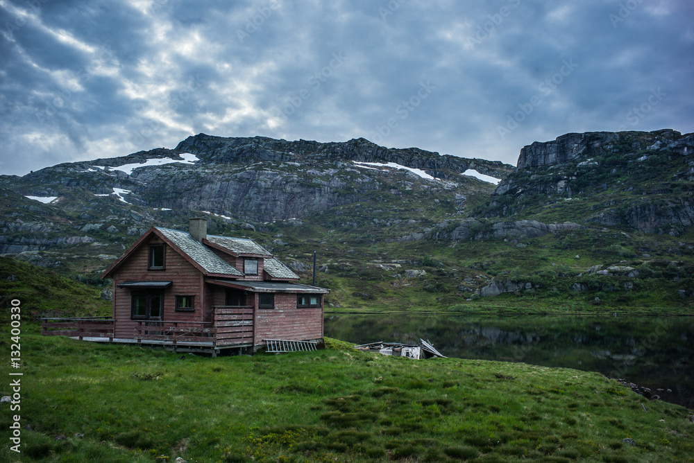 Old house in Norwegian lake and dramatic sky