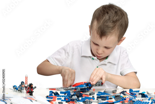 Young boy playing absorbedly with construction kit. With place for a text. photo