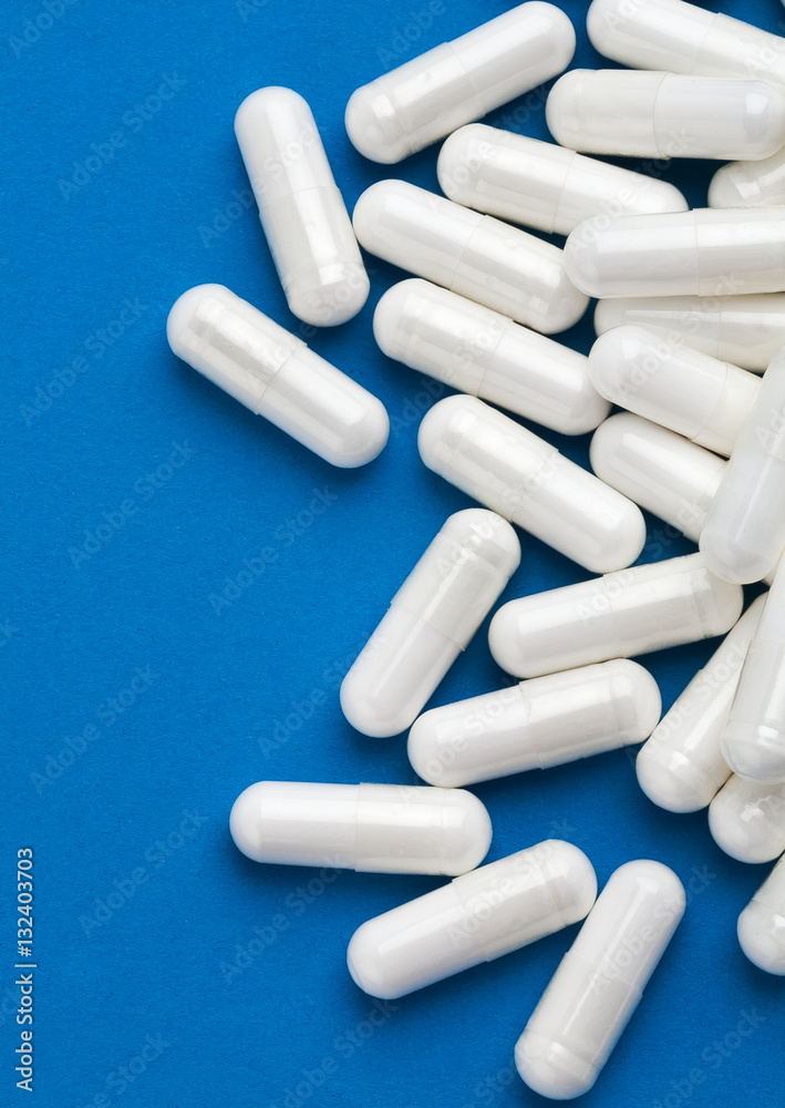 White capsules medications on blue background. Top view, high resolution product. Health care concept White capsules medications on blue background. Top view, high resolution product. Health care concept