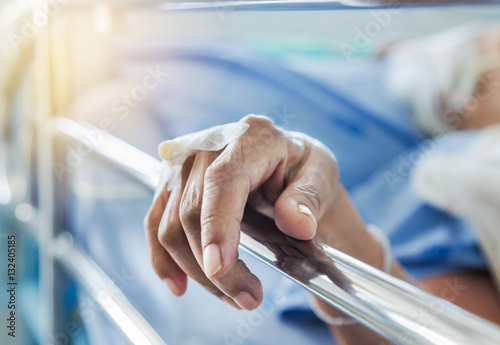 Close up hand of elderly patient with intravenous catheter for injection plug in hand during lying in the hospital bed