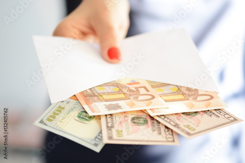 Woman hand holding and passing a white envelope full of money suggesting  money laundering, illegal cash transfer or bribery photo