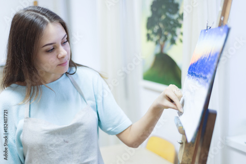 The young beautiful woman draws a chalk landscape