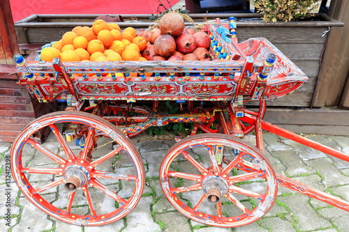 Obraz na plátně Red painted cart containing oranges and pomegranates