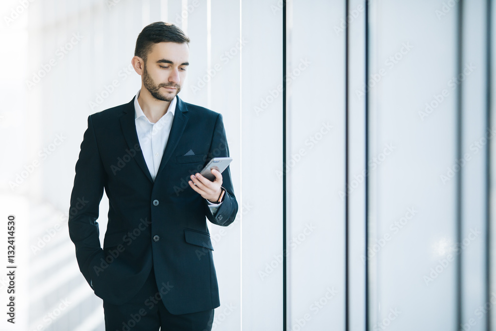 Handsome businessman in suit read sms on phone in terminal Handsome businessman in suit read sms on phone in terminal