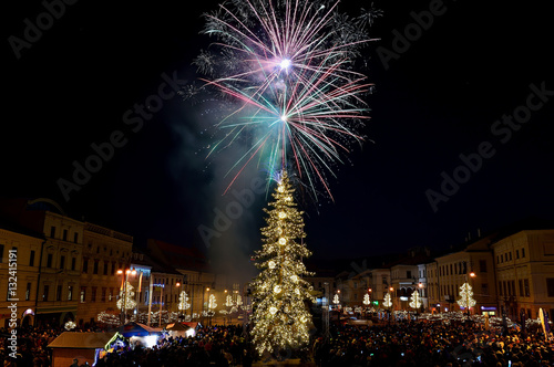 New Year`s Eve firework behind Christmas tree. Celebrating 2017 in Banska Bystrica, Slovakia. Multicolor explosion on dark sky. Foundation day of Slovak republic photo