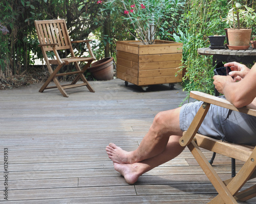 homme en short assis en terrasse dans jardin  photo