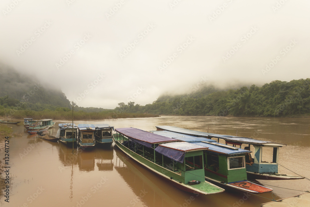 Misty morning over Mekong river with long boats in Laos