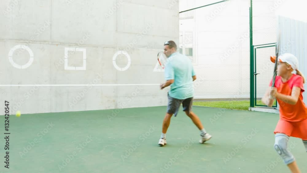 Instructor or coach teaching child how to play tennis use the wall for training