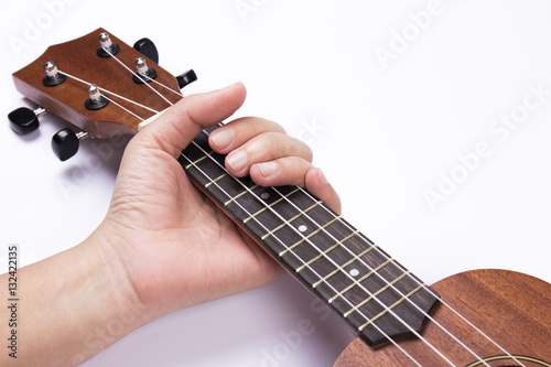 Hand holding ukulele on isolated white background