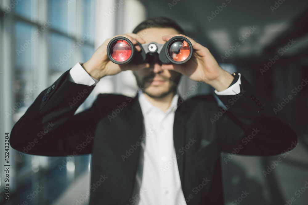 american businessman using binoculars in office