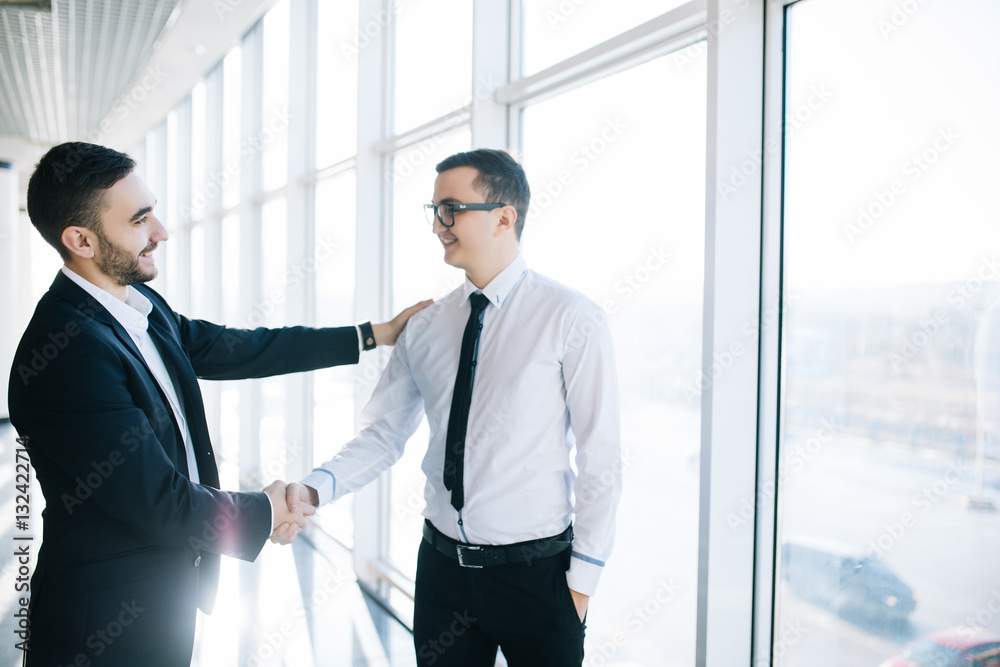 Great job! Two cheerful business men shaking hands and smiling in the background Great job! Two cheerful business men shaking hands and smiling in the background