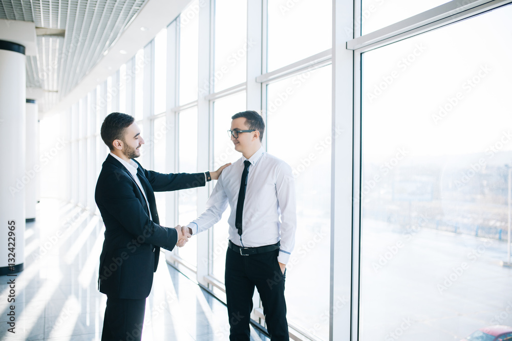 Two business men shaking hands in office with panoramic windows Two business men shaking hands in office with panoramic windows