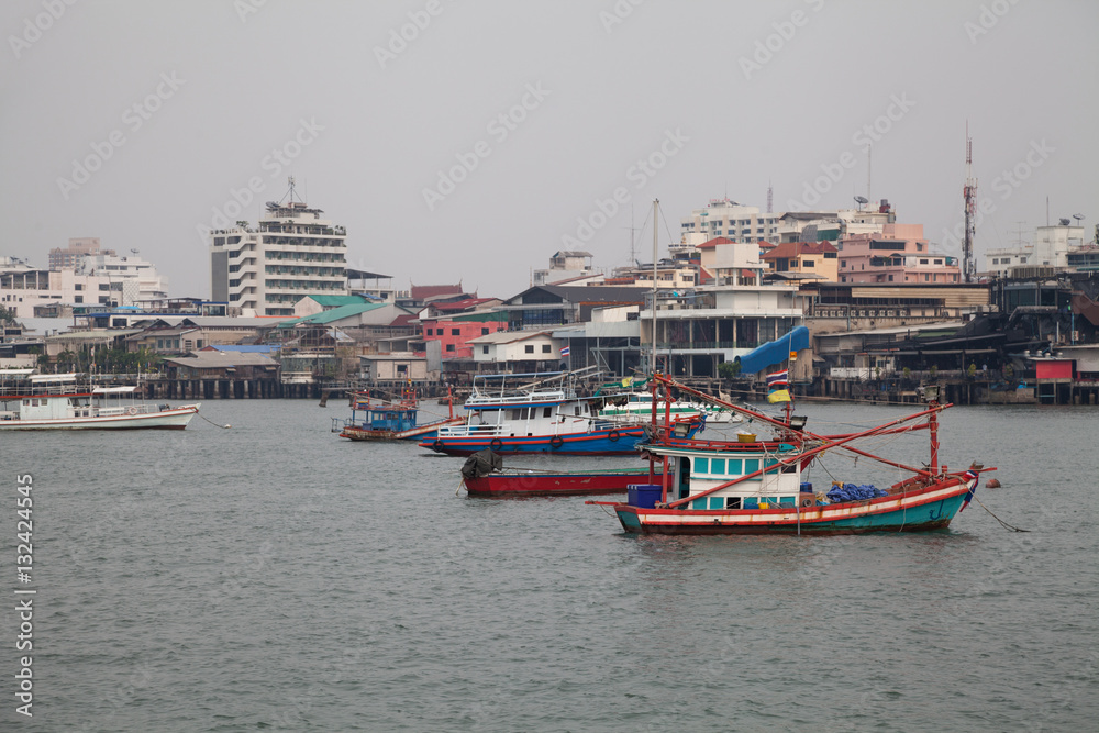 Old colorful fishing boats in a bay in Thailand on a cloudy day