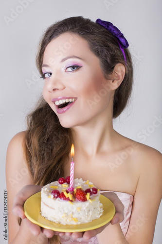 Beautiful happy girl propose a birthday cake with candle