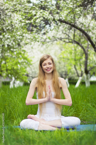 beautiful woman is doing yoga in the blossoming garden