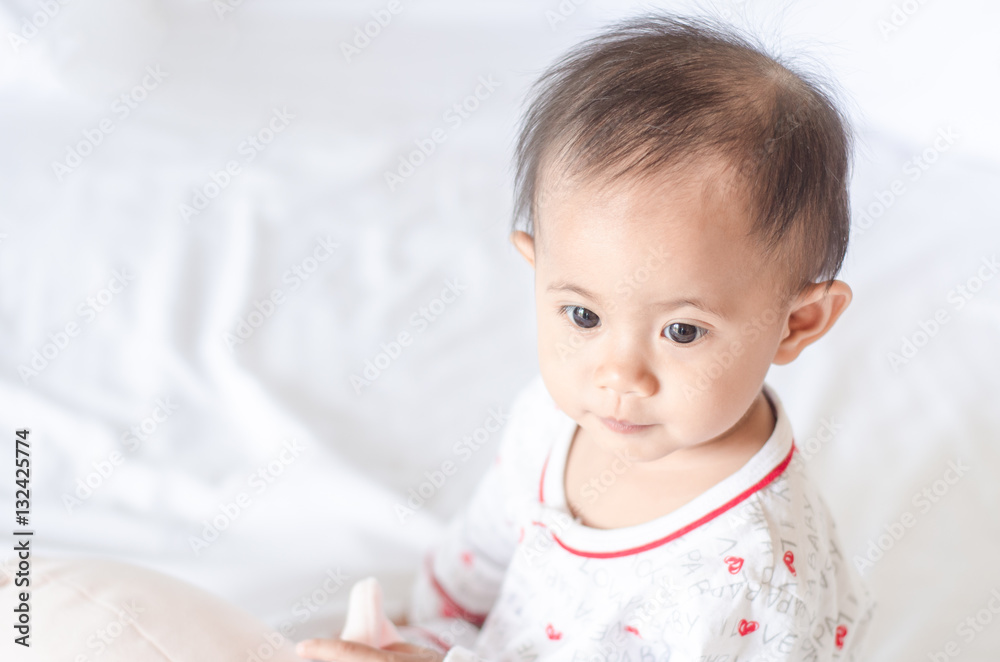 Cute asian baby girl sitting on the bed with lighting background Cute asian baby girl sitting on the bed with lighting background