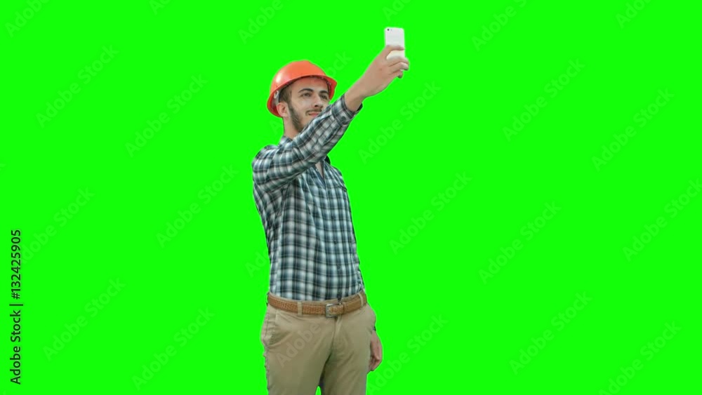 Construction worker using phone to take selfies on a Green Screen, Chroma Key.