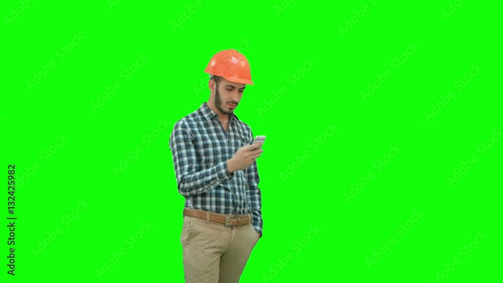 Young manager in helmet using mobile phone on a Green Screen, Chroma Key. Young manager in helmet using mobile phone on a Green Screen, Chroma Key.