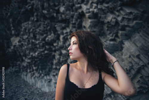 Sexy model in dress posing against the backdrop of the rock