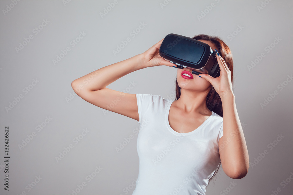 Attractive woman using virtual reality goggles on grey background. VR headset. Attractive woman using virtual reality goggles on grey background. VR headset.