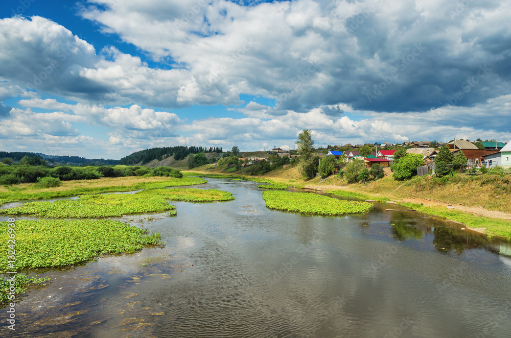 Summer landscape with village by the river