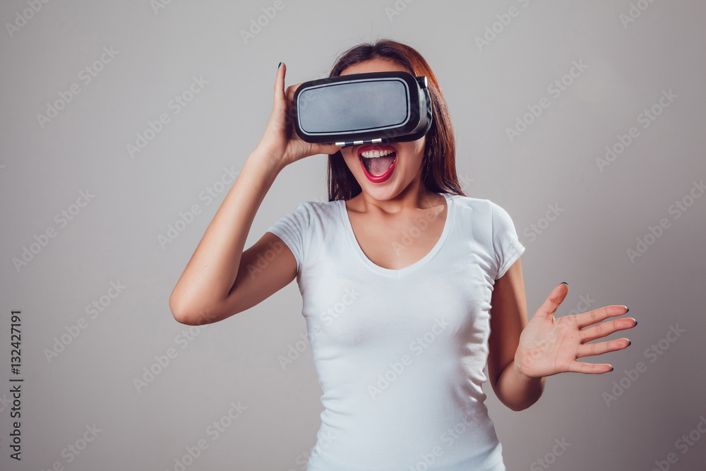 Attractive and happy woman using virtual reality goggles on grey background. VR headset. Attractive and happy woman using virtual reality goggles on grey background. VR headset.