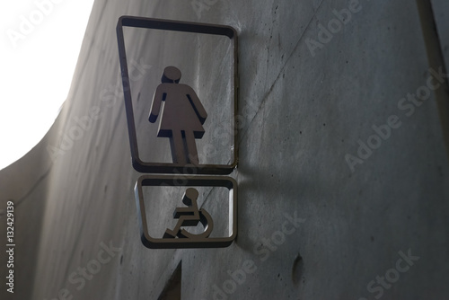 Toilet and disable sign made from stainless steel on concrete wall.