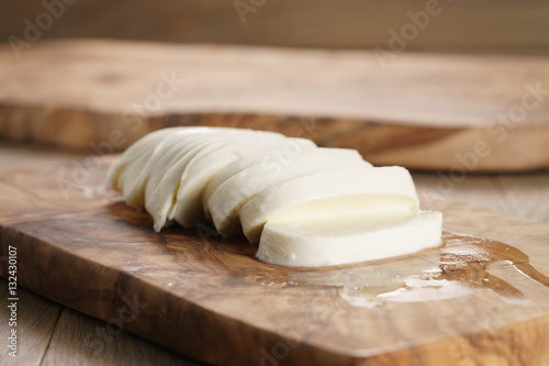 sliced ball of mozzarella cheese on wooden board, shallow focus