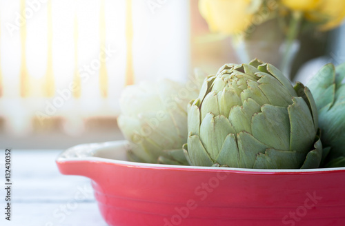 Fresh organic green artichokes in red blow on the table photo