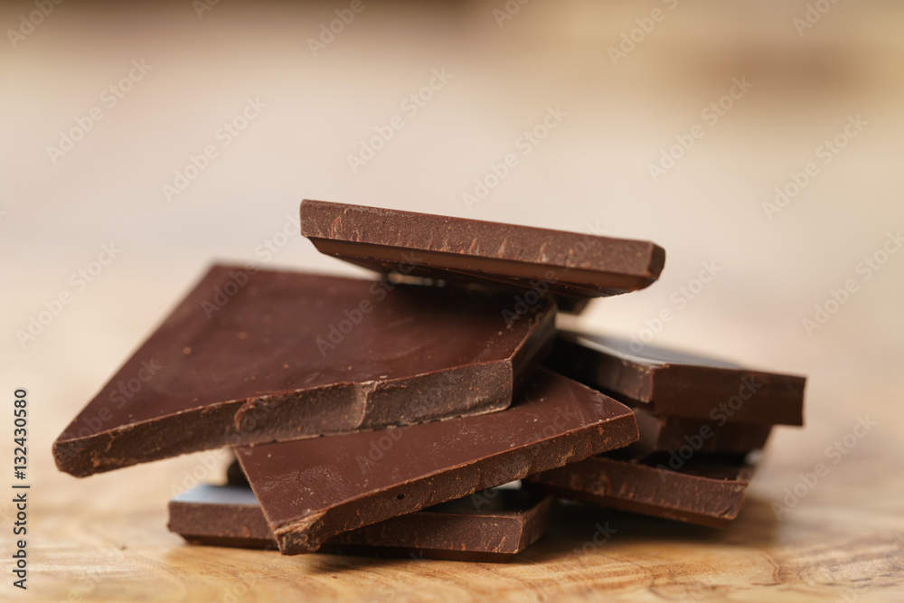 stacked pieces of chocolate bar on wooden table, shallow focus