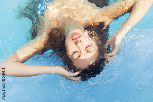 Beautiful brunette woman on the beach in pool alone relaxing