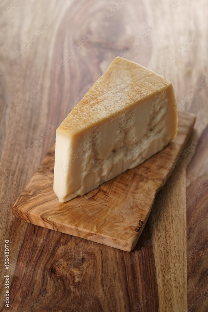 piece of italian parmesan cheese on wooden cutting board, simple rustic photo