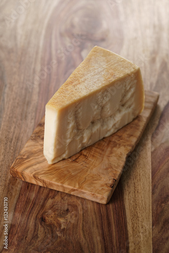 piece of italian parmesan cheese on wooden cutting board, simple rustic photo
