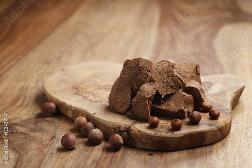 chunks of gianduja with hazelnuts on wood board, premium chocolate dessert