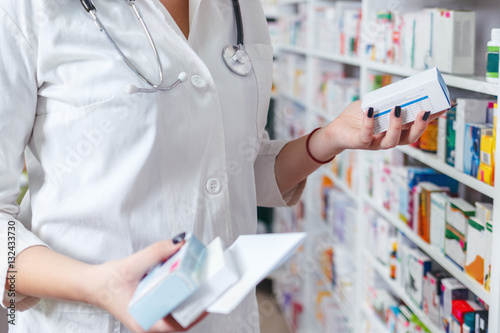 Woman pharmacist holding prescription checking medicine in pharmacy - drugstore. photo