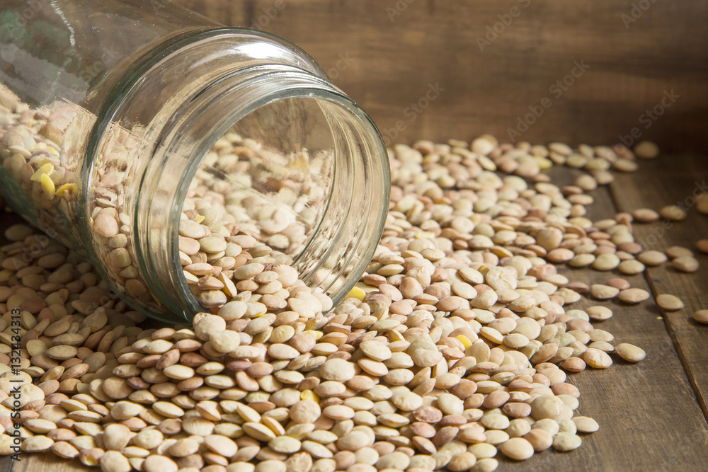 Glass jar with organic lentils on wooden background Glass jar with organic lentils on wooden background