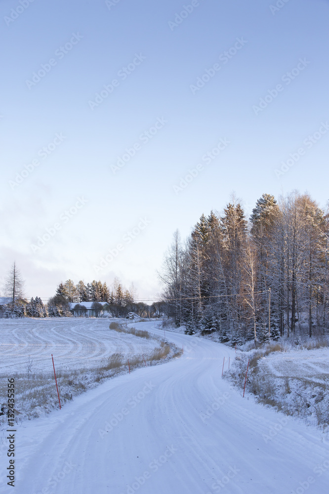 Fototapeta premium Curvy and snowy road in the country side in Finland. 