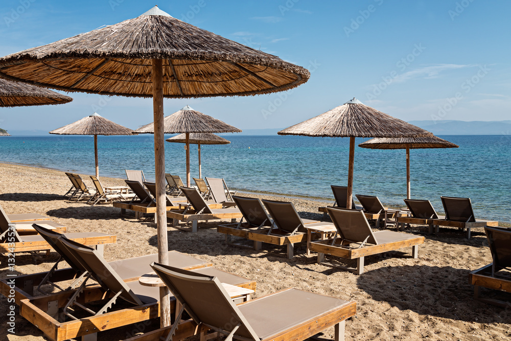 Umbrellas and recliners at the sea, Navagos beach, Chalkidiki, Greece