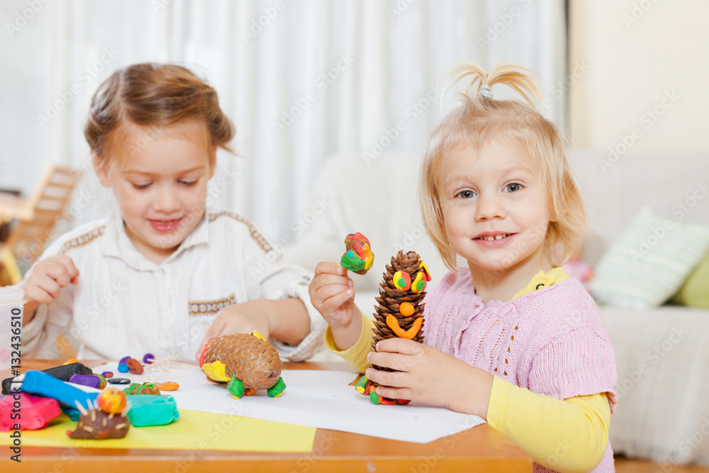 Naklejka premium girls playing with plasticine at house